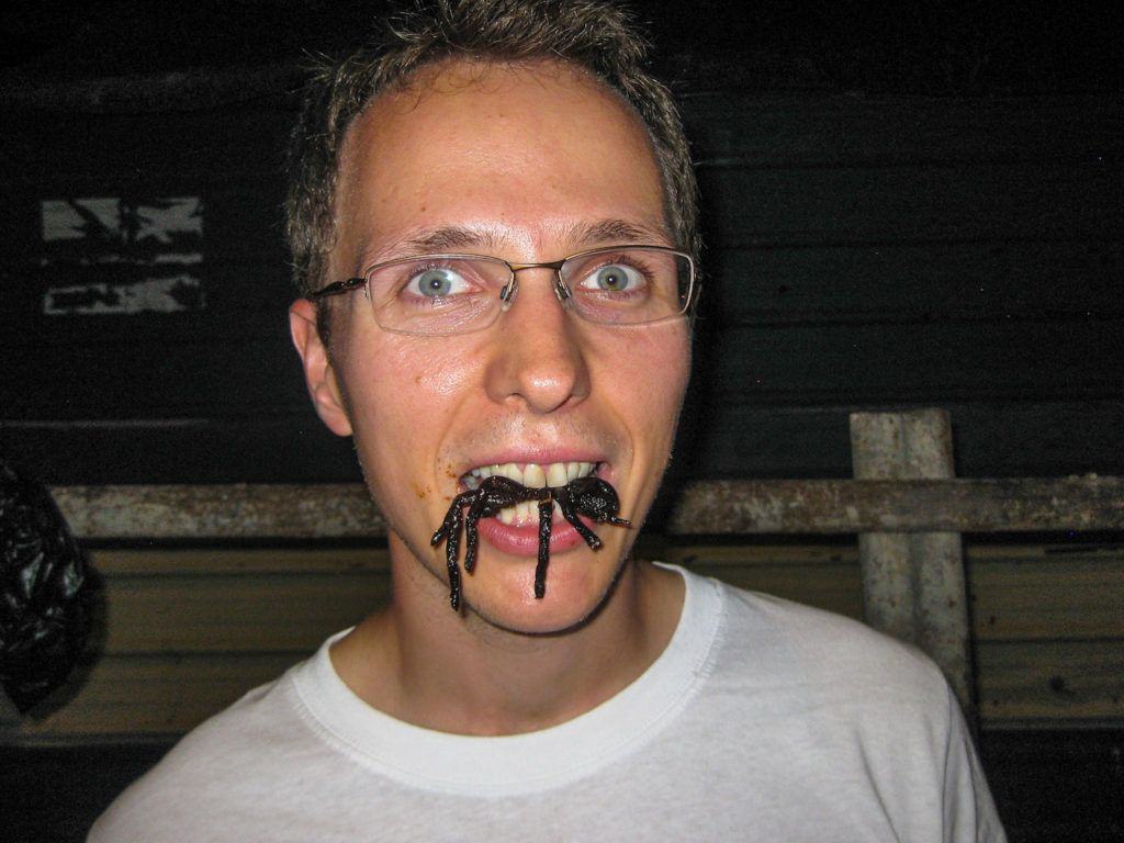 Greasy as heck from the humidity, eating fried tarantula in Cambodia.